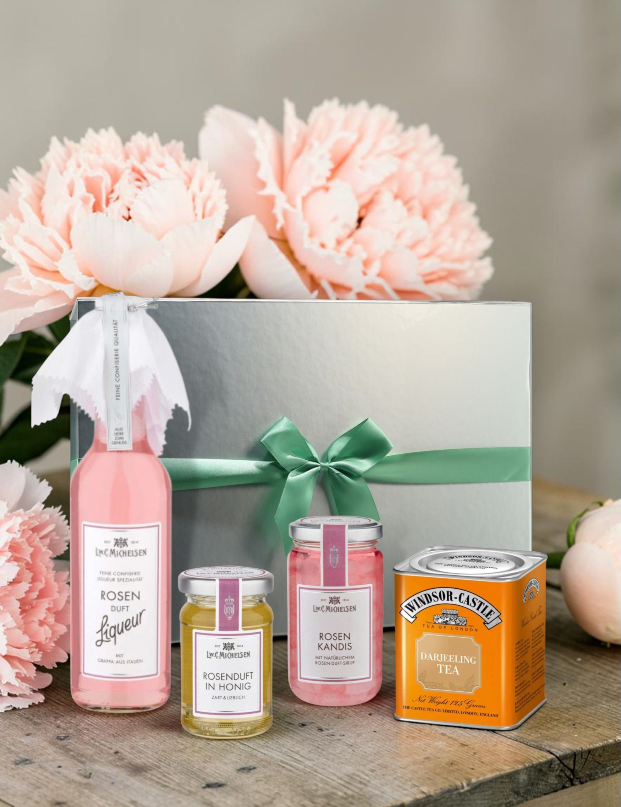 Michelsen Muttertagsset: Rosenduft-Liqueur, Rosenhonig, Rosen-Kandis und Darjeeling Tea in silberner Geschenkbox mit Pfingstrosen.