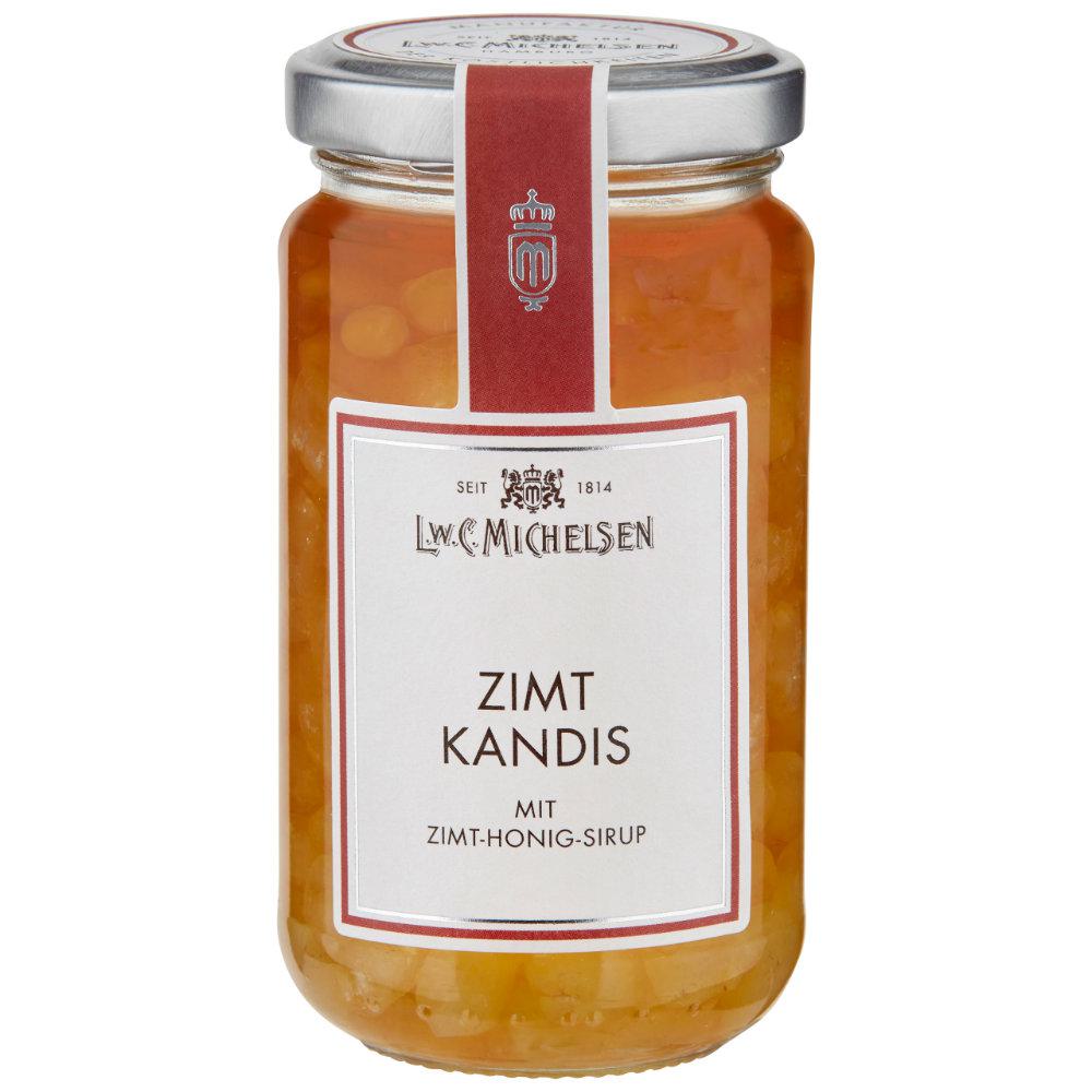 Bernsteinfarbenes Getränk wird in Glas mit Strohhalm eingegossen, umgeben von Kandiszucker und Zuckerlutscher auf Leinen.