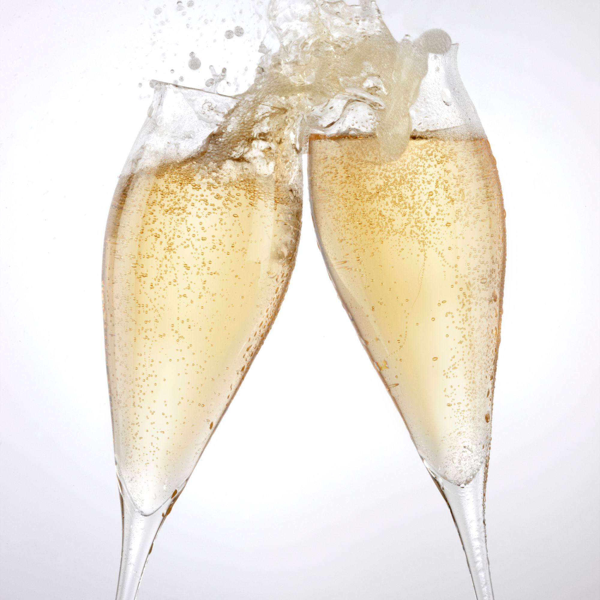 Zwei Champagnergläser stoßen an mit spritzenden Blasen
