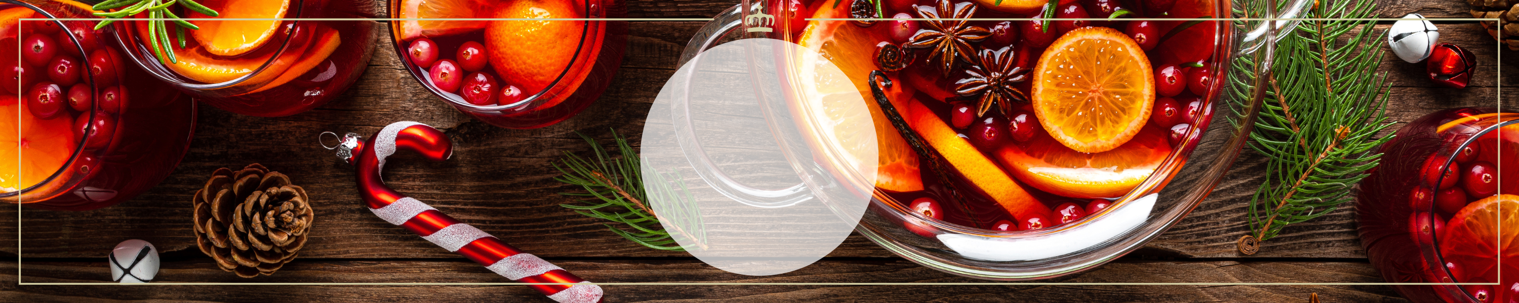 Festlicher Punsch mit Orangen-, Cranberry- und Gewürzaromen, dekoriert mit Tannenzweigen und Zuckerstange