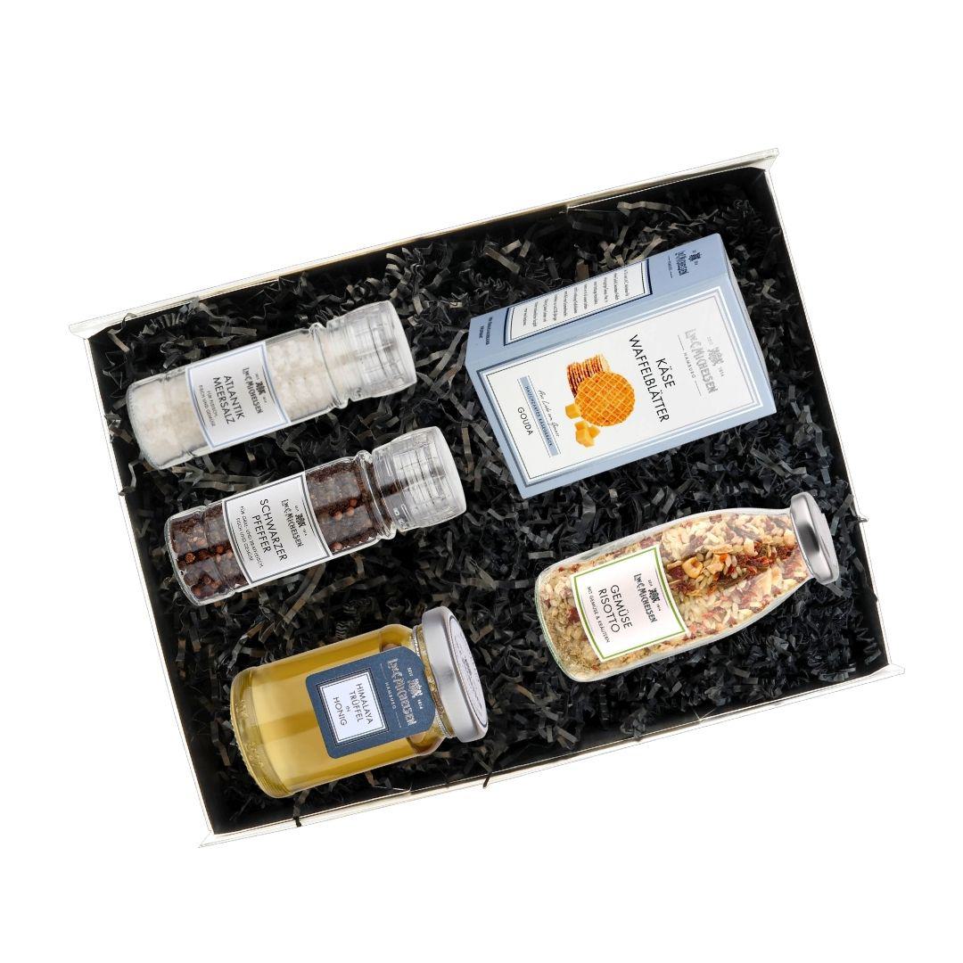 Geöffnete Geschenkbox mit Käsewaffelblättern, Trüffelhonig, Meersalz, Schwarzem Pfeffer und Gemüse Risotto