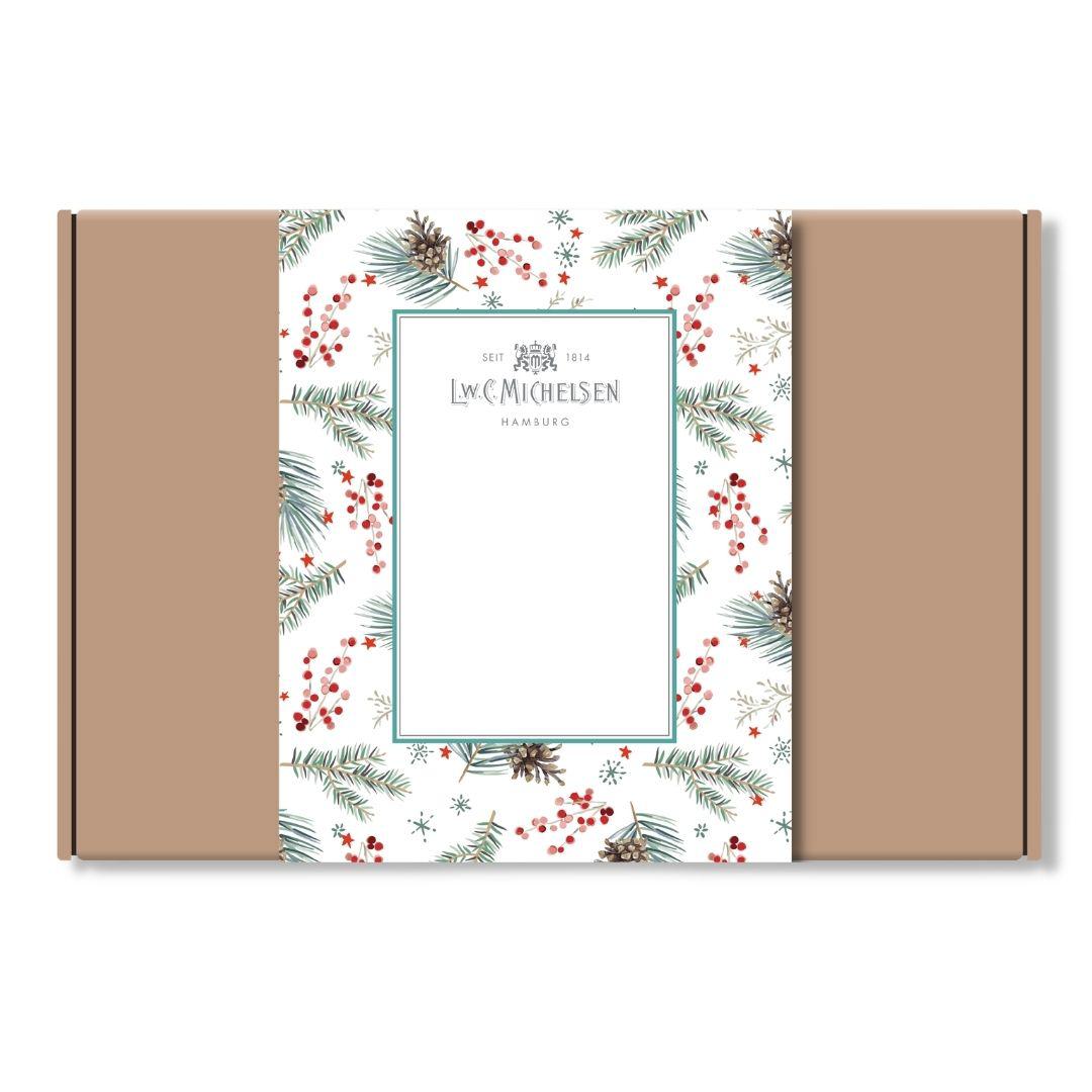 Geschlossene Geschenkbox aus braunem Karton mit weihnachtlicher Banderole mit Tannenzweigen, Zapfen und roten Beeren sowie Logo von L.W.C. Michelsen Hamburg.