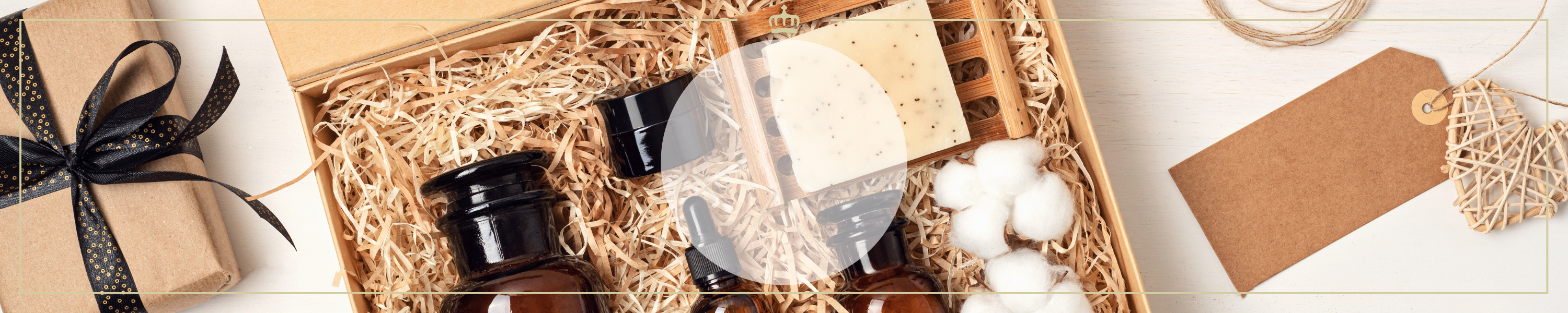 Geschenkset mit braunen Flaschen, Seifenstück, Baumwollbällchen und Dekoration in einer Holzkiste