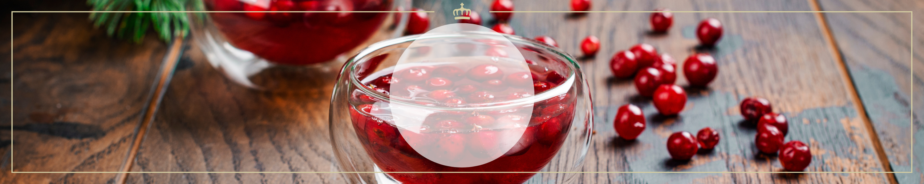 Ein Glas gefüllt mit frischen Cranberries und Flüssigkeit, umgeben von verstreuten Cranberries auf einem Holztisch.