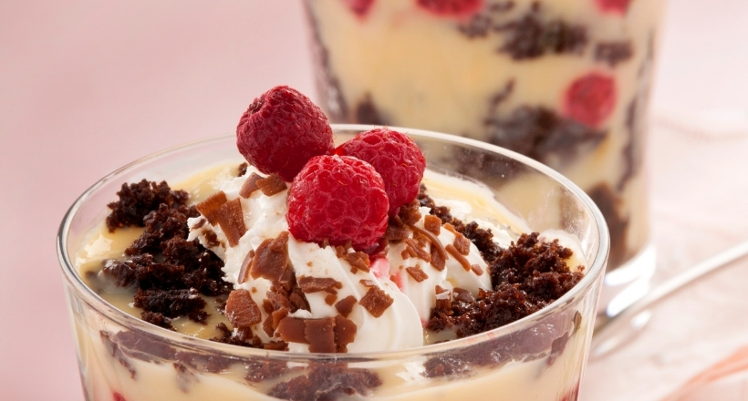 Dessert im Glas mit Schokoladenkuchen, Himbeeren und Sahne dekoriert