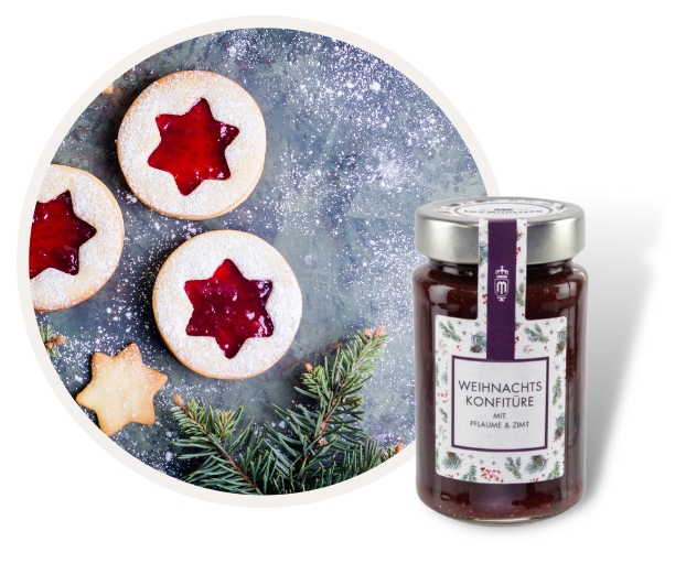 Glas Weihnachtskonfitüre mit Pflaume und Zimt, dekoriert mit Tannenzweigen, neben Weihnachtsplätzchen mit roter Füllung auf einem Tisch