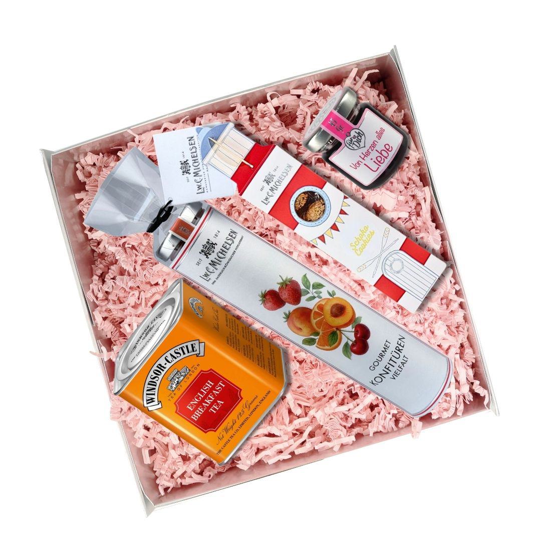 Geöffnete Geschenkbox mit English Breakfast Tea, Mini-Konfitüren, Schoko Cookies und Himbeeren in Alkohol