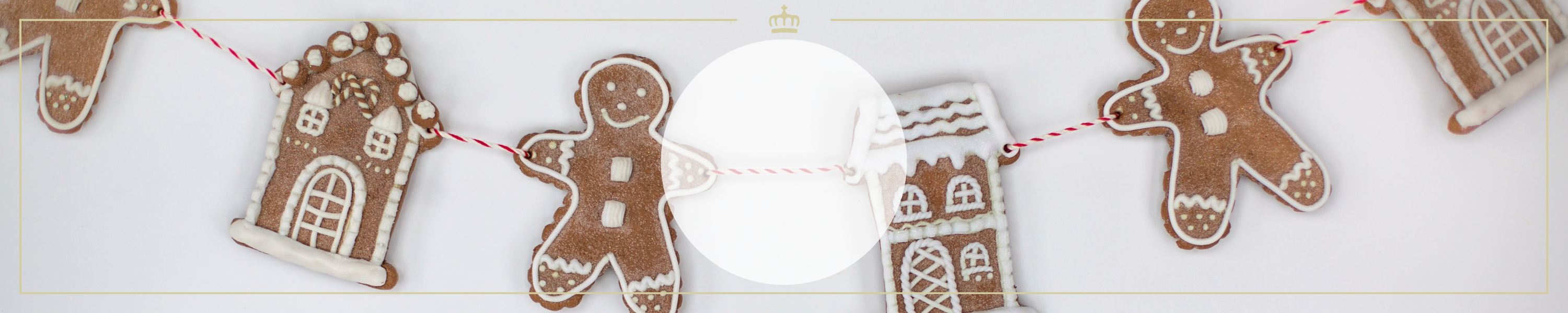 Lebkuchenmännchen und Lebkuchenhäuschen als festliche Dekoration auf einer roten Schnur