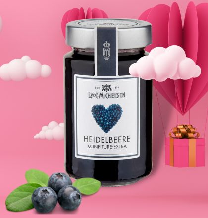 Glas Luc Michel Heidelbeere Konfitüre mit rosa Geschenk und Herzdekor im Hintergrund